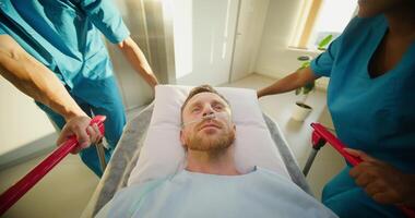 A man is lying on a medical gurney, he is being taken through the hospital. photo