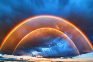 Breathtaking double rainbow arcs across a vibrant sky after a summer rainstorm during evening twilight photo