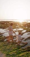 Mother spends time with her daughter on ocean coastline. Family and sunset sunshine video