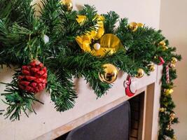 Festive Christmas garland with gold ornaments and yellow bows adorns a fireplace mantel. Perfect for holiday cards, websites, or advertisements, this image evokes warmth and cheer. photo