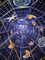 Stunning low-angle view of a dazzling light installation. Blue and warm-white LED lights adorn a geometric framework, creating stars and crescent moons. photo