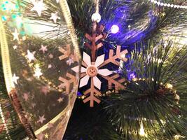 Close-up of a rustic wooden snowflake ornament hanging on a decorated Christmas tree. photo