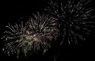 Spectacular fireworks display exploding in the night sky. Vibrant bursts of light and color create a stunning visual, perfect for celebratory themes, holiday promotions, or event backgrounds. photo