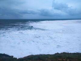 Dramatic ocean landscape featuring turbulent waves crashing under a cloudy sky. Perfect for conveying themes of power, natures force, or overcoming challenges. photo