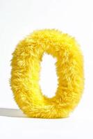 The bright yellow fluffy letter O stands out against a pure white backdrop, emphasizing its soft texture and cheerful appearance photo