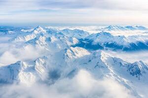 Captivating landscape showcases rugged mountain peaks enveloped in snow and clouds, revealing the beauty of glaciation in the high altitude photo