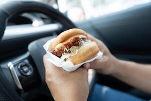 lady holding hamburger to eat in car dangerous photo
