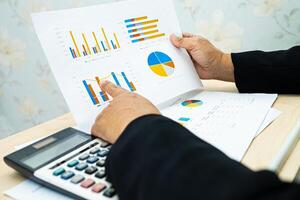 accountant working and analyzing financial reports project accounting with chart graph and calculator in office, finance photo