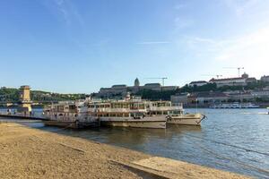 Cruise boats docked on the Danube River in Budapest with view of Buda Castle and Chain Bridge in the background, photographed on April 14, 2024 photo