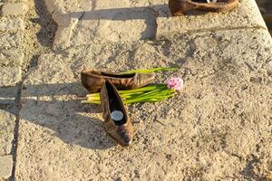 Close-up and wide views of Shoes on the Danube Bank memorial in Budapest with bronze shoes, flowers, and candles along the riverside promenade photo
