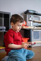 Little boy playing with toys while sitting on the floor at home. Early development, imagination, and childhood learning in a family environment. Child psychology, home life, and early education themes photo