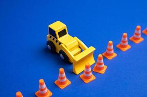 A yellow bulldozer pushes back a boundary of cones. The concept is to expand what is permitted, remove restrictions and rules. Idea of expanding freedom, lifting regulations, or redefining boundaries. photo