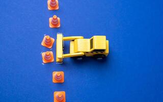 A yellow bulldozer crosses the line of cones. The concept of crossing boundaries and removing restrictions. Revision of norms and rules. Breaking through set norms, pushing past limitations photo