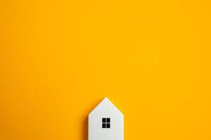 A small house figure appears to be peeking out of the frame against a yellow background. Real estate and housing. Purchase, sale and rent. photo