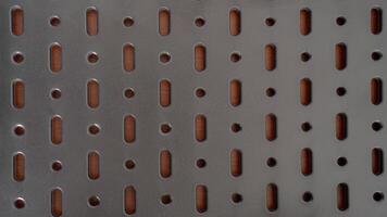 A close-up of a perforated metal surface with a repeating pattern of oval and circular holes. The dark, industrial aesthetic creates a sense of mystery and intrigue photo