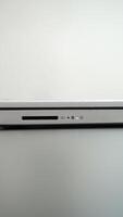 Close-up of a sleek silver laptop with a visible SD card slot and power button. The laptop rests on a clean, white surface. photo