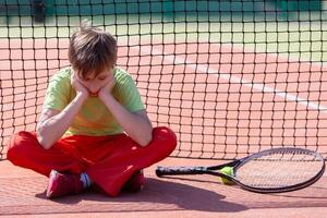 The child sits at the net with a racket. H photo