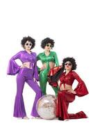 Three female pop stars in neon clothes pose in front of a silver ball. photo