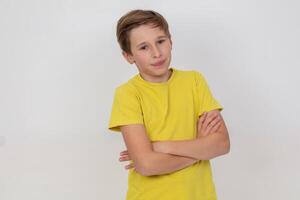 A young guy in a yellow shirt stands with his arms crossed and looks at the camera. He is in a serious or thoughtful mood. photo
