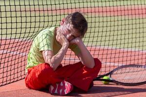 The child sits at the net with a racket. photo
