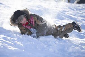 Happy little boy is rolling down a snow slide. Child in winter. photo