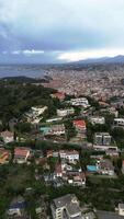 Aerial view of a coastal city with a mix of residential buildings and greenery. The sky is overcast, and the sea is visible in the background. video