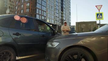 A large bearded man, who is the driver, gets out of the car and opens the hood with displeasure. He is assessing the consequences of a collision with another vehicle. video