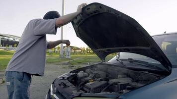 Young man, in state of horror, opens hood of his car, and smoke begins to pour out from underneath it, indicating serious problem with engine and overheating. video