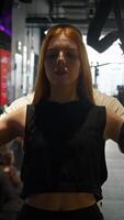 Young and attractive red-haired woman with help of her personal trainer pulls herself up with the help of rings. trainer helps her perform exercises, ensuring proper technique in gym. video