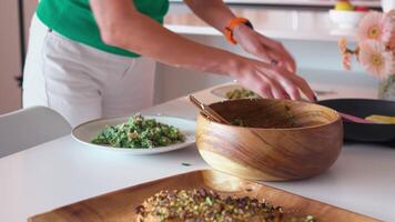 Woman's hands serving salad from large wooden bowl into plate video