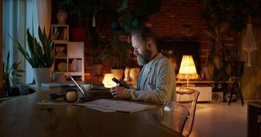 The man talks on a mobile phone and uses a laptop while working from home. photo