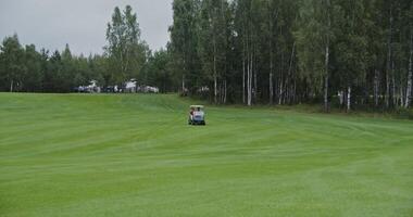 Panoramic view of golf course with the golf car driving through it. Two men are about to play golf while moving from place to place in an electric car on a rainy day photo