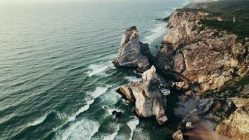Drone flies over the rocks on the seashore, a bird's-eye view on a summer day. Foamy sea waves beat against the shore photo