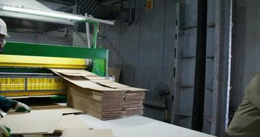 Two men in uniform talk while working at a paper mill. They stand near the cutting machine photo