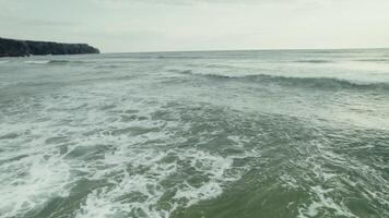 The drone flies low and fast over the sea with large waves. Rocks on the shore photo