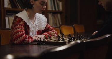 Two young adults intensely concentrating while playing chess in a library setting. photo