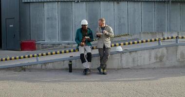 Two workers in uniform are having lunch sitting outside near the factory. photo