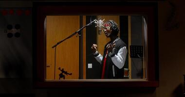 The rapper is recording a song in a recording studio. View through the window photo