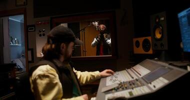 The rapper is recording song in the studio. The sound engineer controls the recording process photo