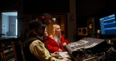 The sound engineer talks to the musicians after recording the song in the studio. They are sitting in front of the equipment in the control room photo