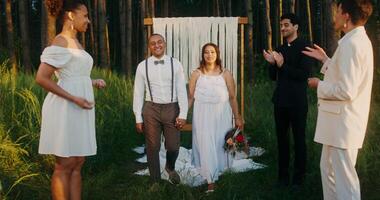 The bride and groom hold hands passing by the guests after the wedding. Guests shower the young with rice photo