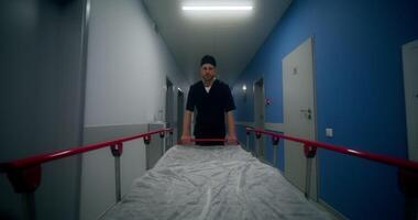 An orderly carries an empty gurney down the hospital photo