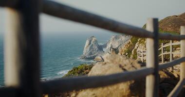 View of the sea washing the rocky shores and ledges. View from the top of the mountain from the observation deck through the fence photo