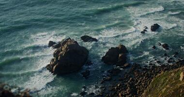 Top view of a rocky shoreline with sea waves crashing against the rocks. photo