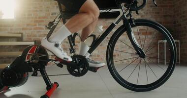 A young man using an exercise bike n a modern home interior, dynamic from man's feet to his face photo