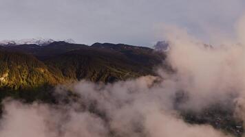 Scenic view of mountain valley from a bird's eye view through the clouds. A village in a lowland between gently sloping mountains overgrown with dense forest, drone . Austria, Alps photo