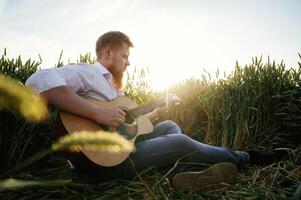 Guitar in hands. Man in white shirt ,,is, on, the agricultural field photo