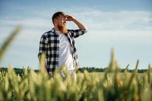 Looking, far, away. Man in white shirt is on the agricultural field photo