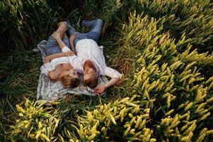 Resting, lying ,down,, top view. Lovely couple are on the green agricultural field together photo