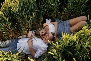 Top view, lying down. Lovely, couple are on the green agricultural field together photo